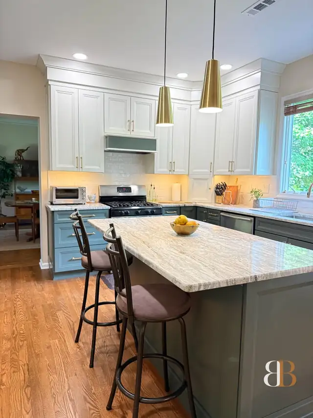 Doylestown kitchen with vanilla painted upper cabinets, a sage green island with a Fantasy Brown stone top, bar stools, brass cone pendants and oak floors