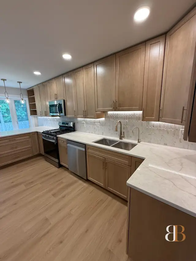 Bala Cynwyd kitchen with natural maple stained cabinets to the ceiling, a marble backsplash, white stone counters, an undermount sink and under-cabinet lighting