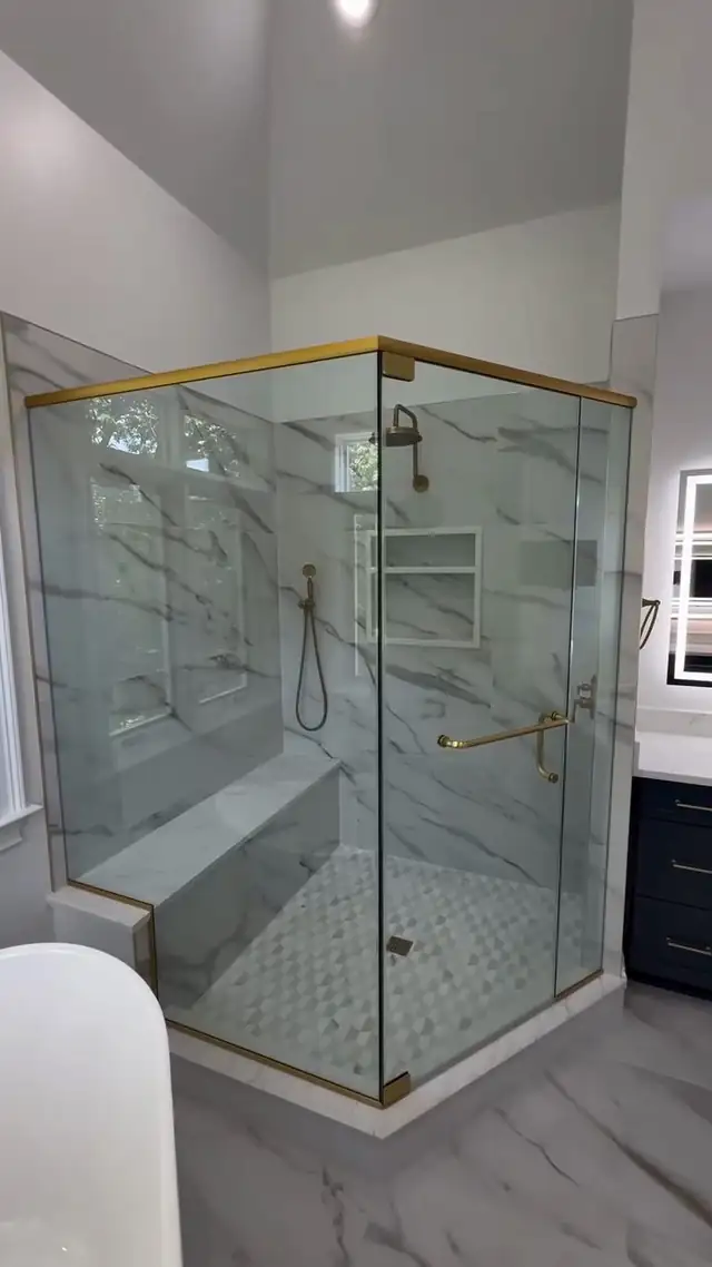 Lansdale walk-in shower with marble-veined 24x48 porcelain walls, a built-in bench, a recessed niche, a mosaic floor and a brass-trimmed frameless glass enclosure