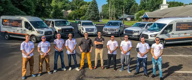 B&B Associates Creations crew lined up in matching shirts in front of the company's work vans and trucks